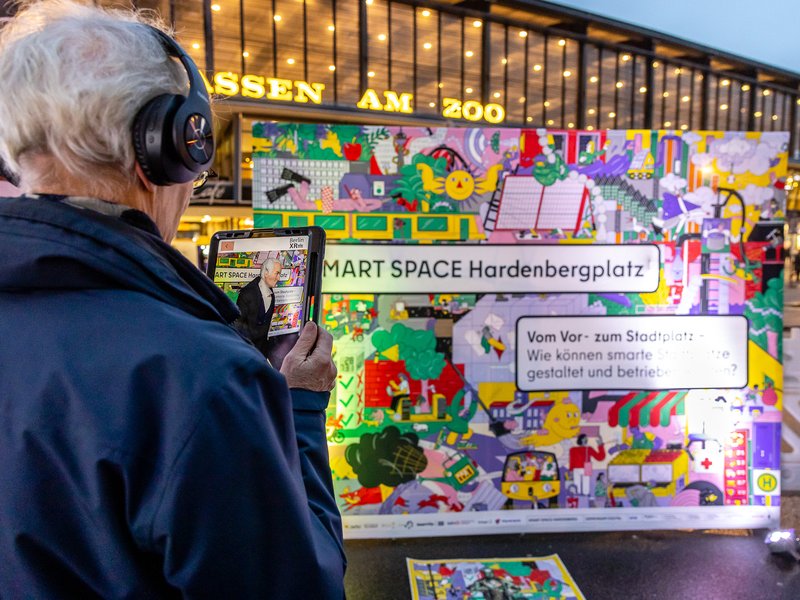 Das Foto zeigt eine Person mit einem Tablet, die sich die Augmented Reality Projektion von Karl August von Hardenberg ansieht.